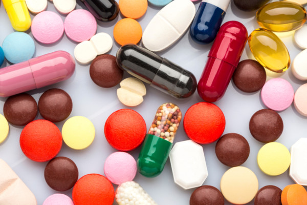 Scattered colorful medical pills and capsules on white background