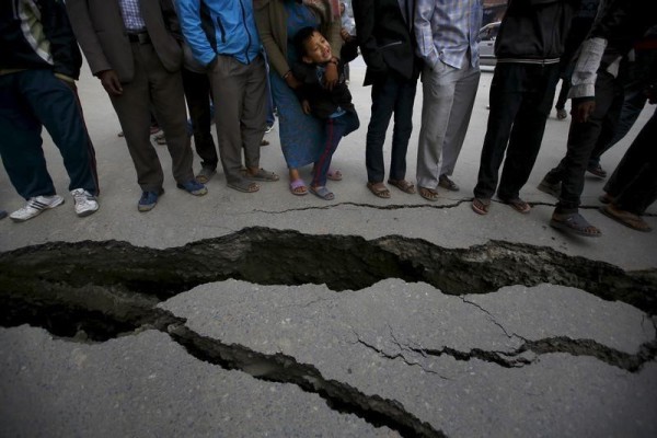 People gather near the cracks on the road caused by an earthquake in Bhaktapur, Nepal April 26, 2015. Rescuers dug with their bare hands and bodies piled up in Nepal on Sunday after an earthquake devastated the heavily crowded Kathmandu valley, killing at least 1,900, and triggered a deadly avalanche on Mount Everest.  REUTERS/Navesh Chitrakar      TPX IMAGES OF THE DAY      - RTX1AANP